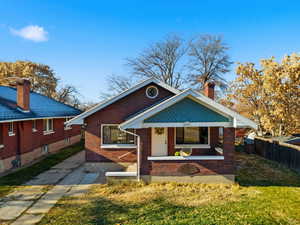 Bungalow-style house featuring a chimney, a porch, and brick siding