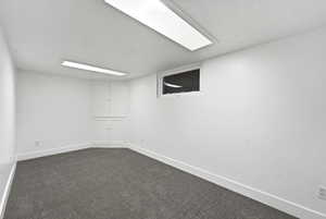 Finished below grade area featuring dark carpet and baseboards
