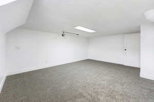 Additional living space featuring a textured ceiling and carpet flooring