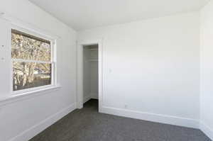 Unfurnished bedroom with dark colored carpet and a walk in closet