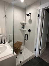 Bathroom with vanity, a marble finish shower, and dark tile patterned floors