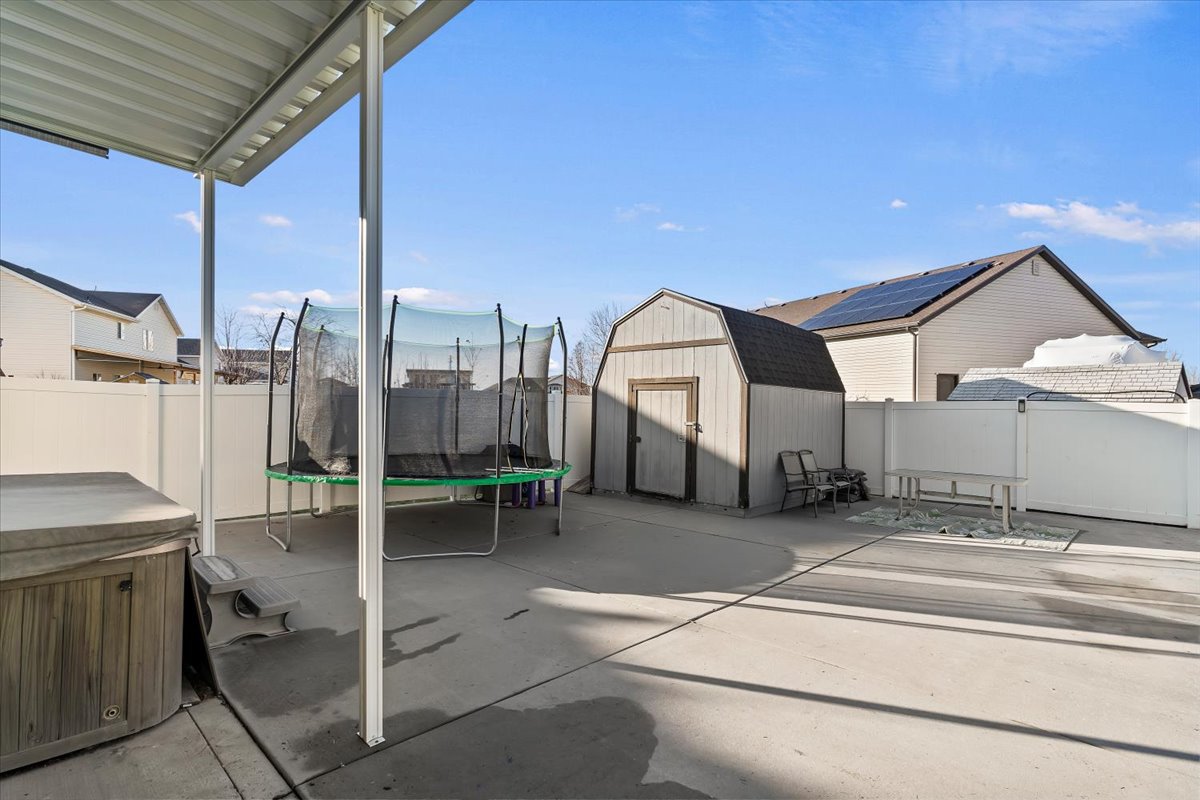 Fenced backyard with a storage shed, a hot tub, and a patio area