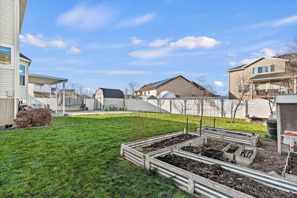 Fenced backyard with a vegetable garden, a patio area, and a residential view