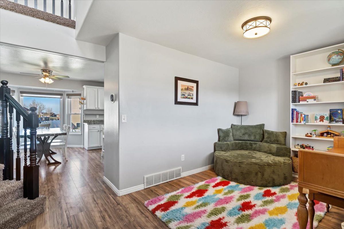 Living area featuring stairway, dark wood-type flooring, and ceiling fan
