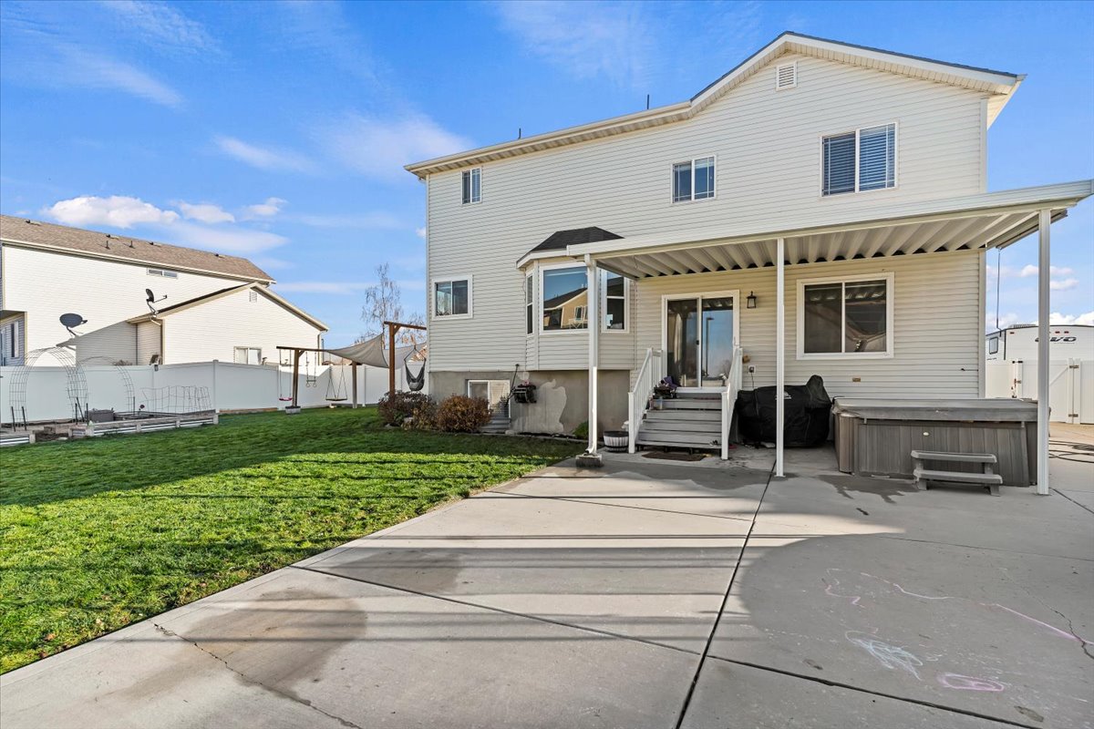 Rear view of property featuring a hot tub and a patio area