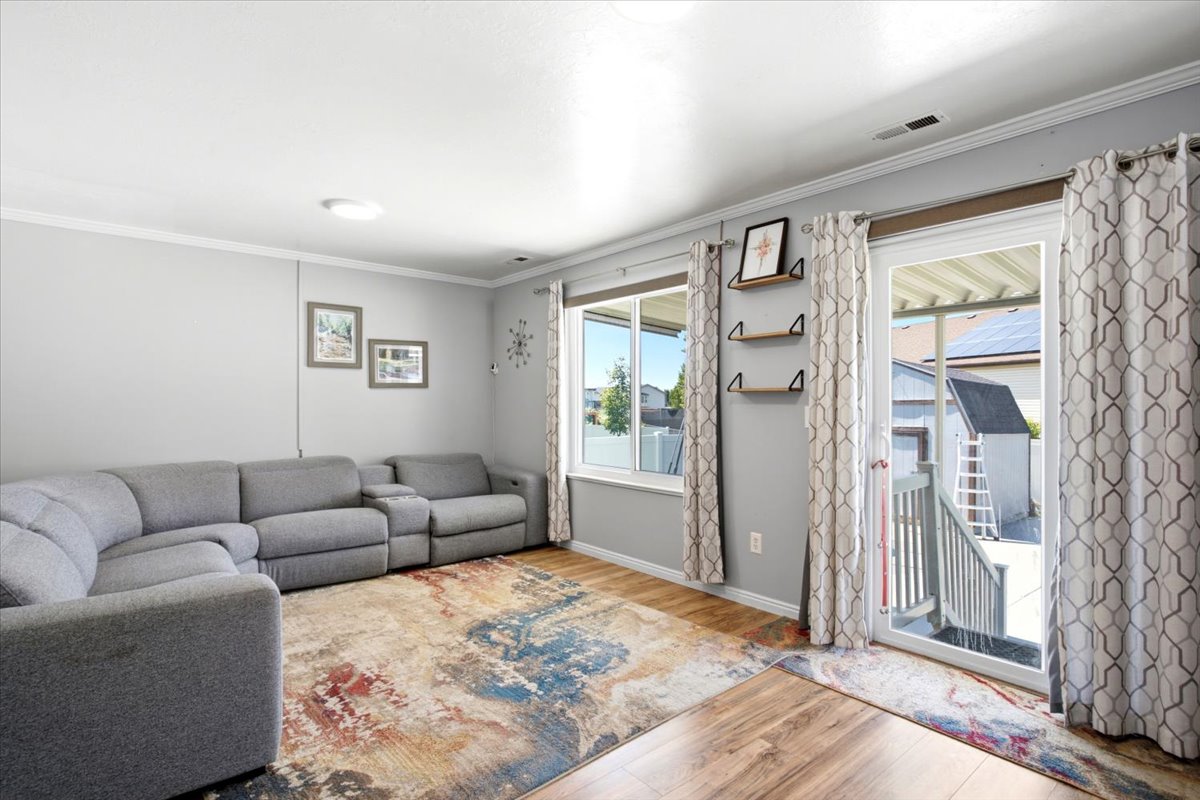 Spacious room featuring wood-finish flooring, light grey wall paint, and white crown molding