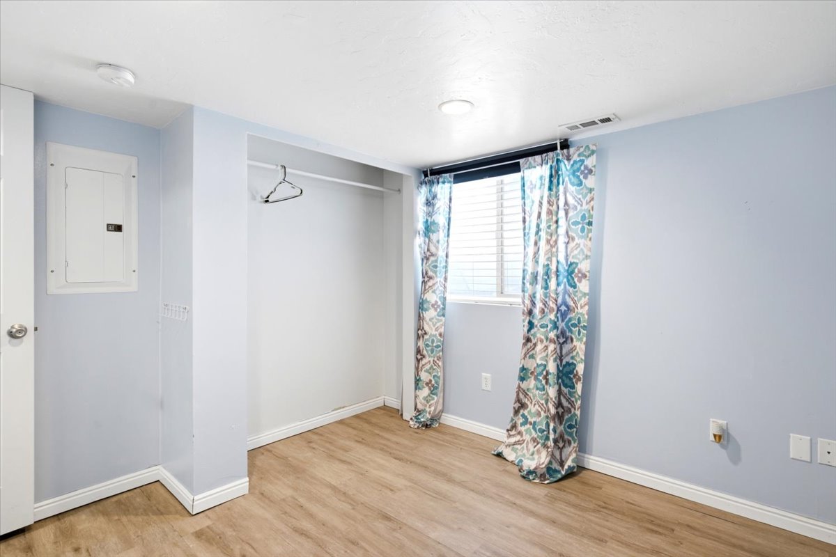 Room featuring wood-finish flooring, a built-in closet, and a window with blinds