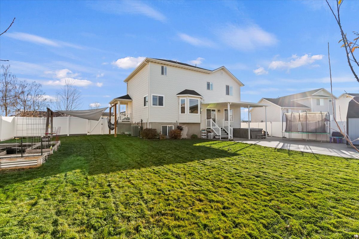 Rear view of property featuring a fenced backyard, a patio, a hot tub, and a trampoline