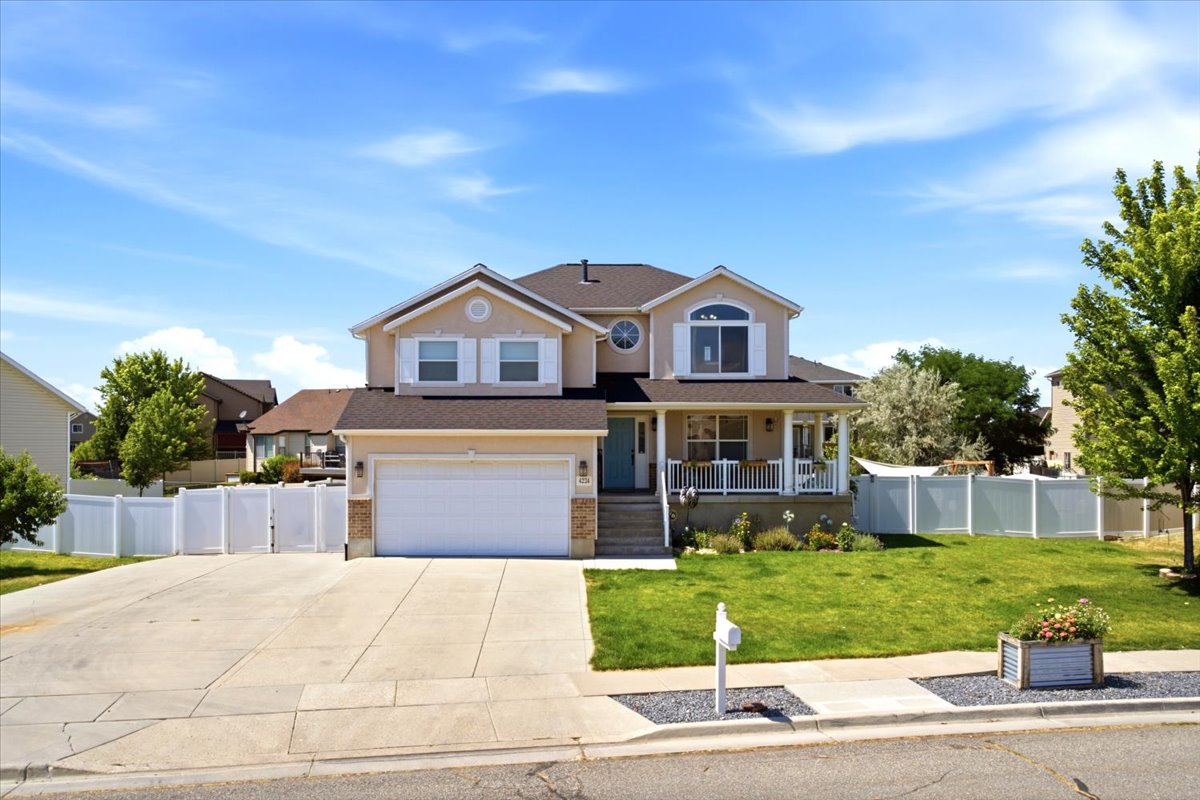 Two-story residence featuring a covered front porch, white railing, and an attached two-car garage with stone accents