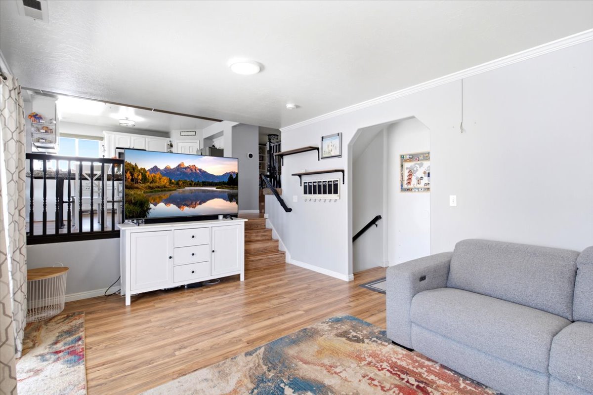 Open-concept living area featuring wood-finish flooring, white crown molding, and a partial wall with black balusters