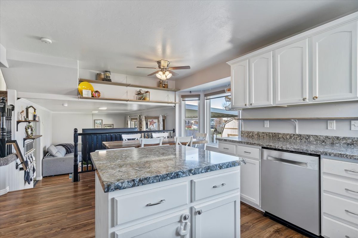 Kitchen featuring white cabinets, stainless steel dishwasher, dark wood-style floors