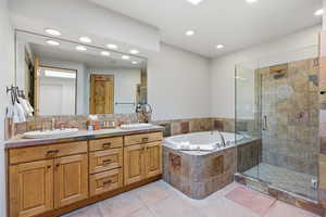 Full bath featuring a garden tub, double vanity, recessed lighting, and a shower stall