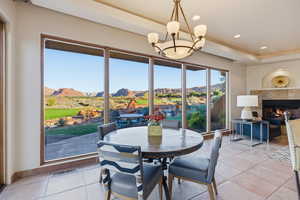 Dining room featuring a mountain view, a tile fireplace, a tray ceiling, recessed lighting, and a chandelier