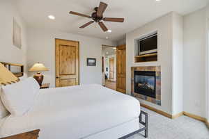Bedroom with a tile fireplace, light colored carpet, ceiling fan, and recessed lighting