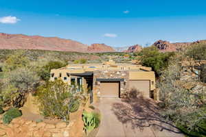 Adobe home with stucco siding, a mountain view, stone siding, and concrete driveway