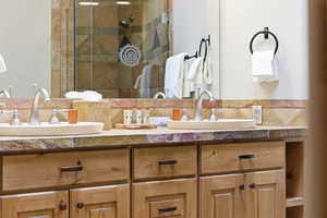 Full bathroom with double vanity and a shower stall