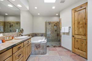 Full bath featuring a bath, vanity, and tiled shower