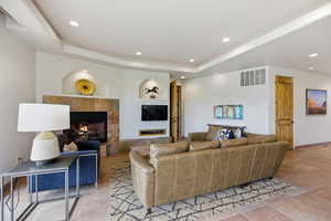 Living area featuring a tile fireplace, a tray ceiling, and recessed lighting
