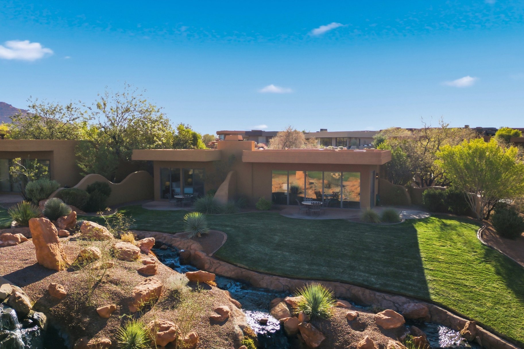 Rear view of property with a patio area, stucco siding, and a lawn