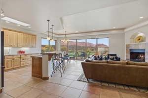 Living area with a chandelier, a mountain view, a raised ceiling, a tiled fireplace, and recessed lighting