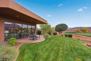 View of green lawn featuring a patio area and a mountain view