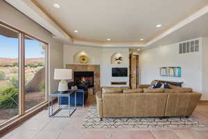 Living area featuring a tile fireplace, a raised ceiling, recessed lighting, light tile patterned floors, and a mountain view