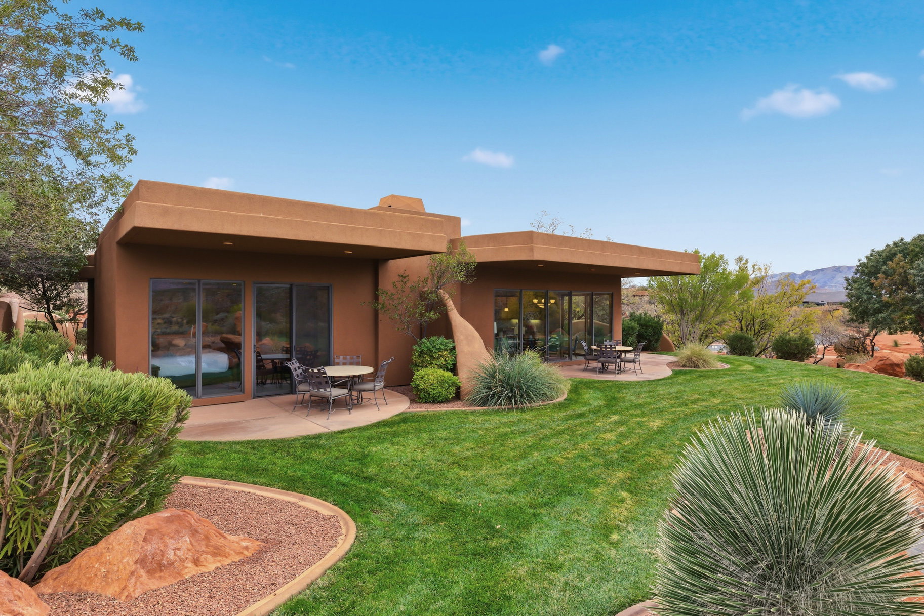 Back of property featuring a patio area, a lawn, and stucco siding