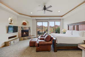 Carpeted bedroom with a fireplace, access to outside, a raised ceiling, a ceiling fan, and recessed lighting