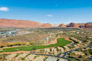 Aerial view of property's location featuring a golf course, a mountain backdrop, and nearby suburban area
