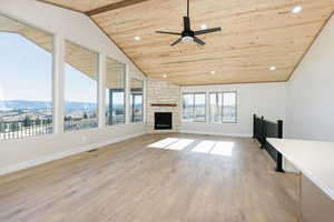 Unfurnished living room with wooden ceiling, a stone fireplace, recessed lighting, light wood-style floors, and a mountain view