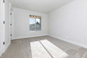 Spare room featuring light colored carpet and baseboards