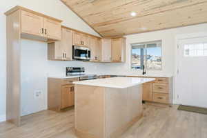 Kitchen with light brown cabinetry, wooden ceiling, appliances with stainless steel finishes, a center island, and light wood-style floors
