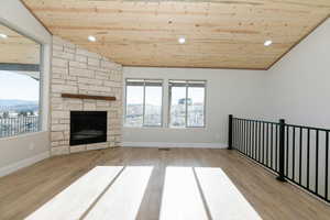 Unfurnished living room featuring wood ceiling, recessed lighting, a stone fireplace, and light wood-style floors