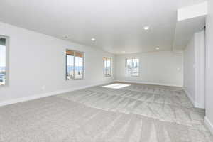 Unfurnished room featuring healthy amount of natural light, light colored carpet, and recessed lighting