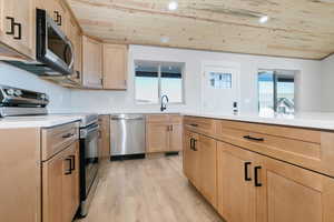 Kitchen featuring wooden ceiling, appliances with stainless steel finishes, healthy amount of natural light, light brown cabinets, and light wood-style floors