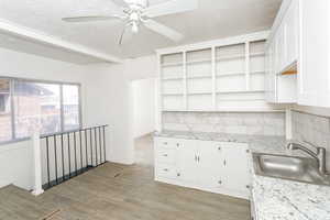Kitchen featuring open shelves, white cabinets, light wood-style floors, light stone counters, and ceiling fan