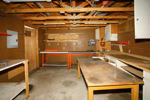 Misc room with unfinished concrete floors and electric panel