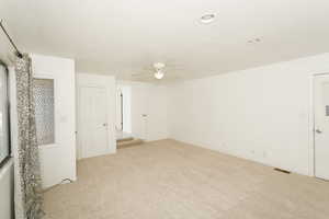 Spare room featuring a textured ceiling, light carpet, and ceiling fan
