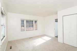 Unfurnished bedroom featuring light carpet and a closet