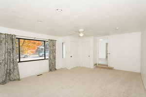 Empty room featuring a textured ceiling, carpet flooring, and ceiling fan