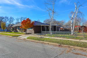 View of front of house with a fenced front yard, driveway, a carport, and a shingled roof