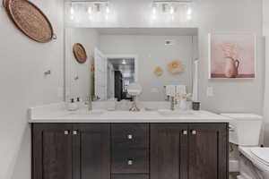 Full bathroom with double vanity and toilet