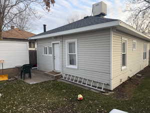 Back of property with roof with shingles, a chimney, a yard, and a patio