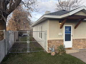 View of home's exterior with stone siding, a gate, a chimney, and stucco siding