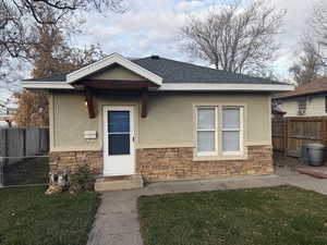 View of front of house with stone siding, stucco siding, and a shingled roof