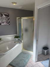 Bathroom featuring light tile patterned flooring, a stall shower, and a whirlpool tub