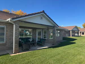 Rear view of house featuring a patio area, a lawn, outdoor lounge area, and brick siding
