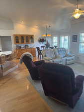 Living area with ornamental molding, ceiling fan, vaulted ceiling, and light wood finished floors