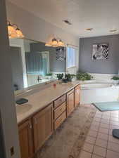 Full bathroom featuring light tile patterned floors, a garden tub, and double vanity