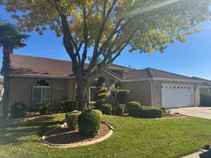 Single story home with a front lawn, concrete driveway, an attached garage, and brick siding